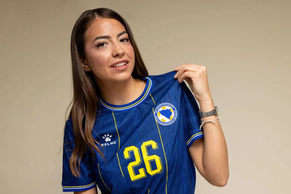 Frau trägt das Bosnien KELME Heimtrikot WM 2026 – Lifestyle-Portraitaufnahme in Blau